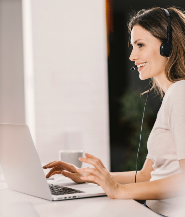 A smiling receptionist with headset and computer.